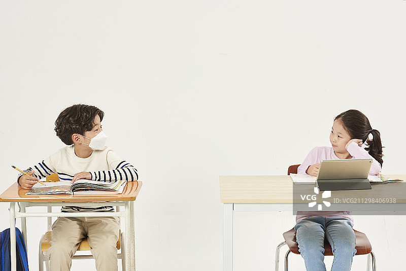 戴着防雾霾口罩学习的男孩和使用平板学习的女孩图片素材