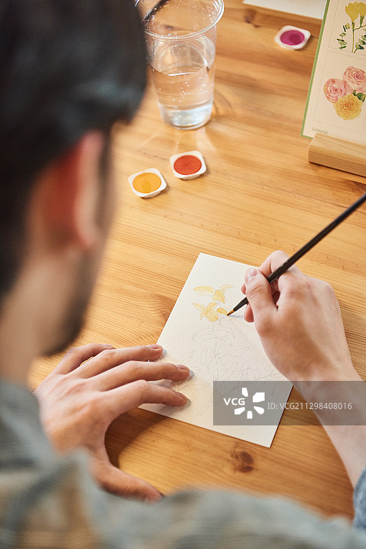 男人坐在桌旁在白纸上绘画图片素材