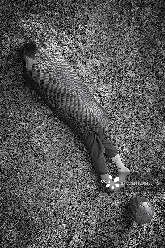 在草地上裹着瑜伽垫的男孩图片素材