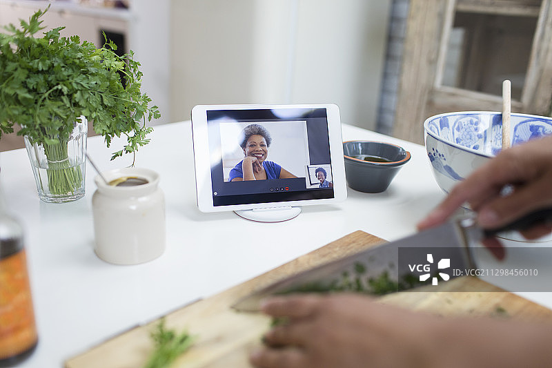 女人在平板电脑屏幕上烹饪和视频聊天图片素材