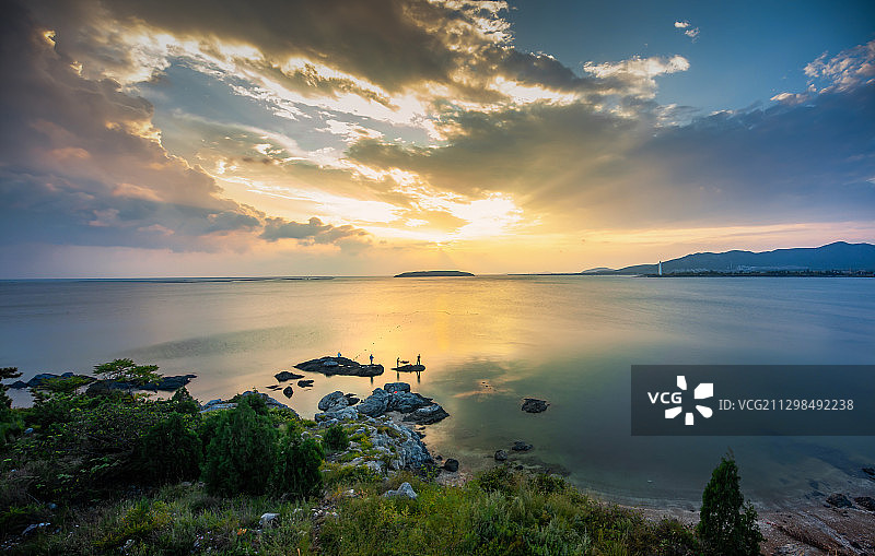 中国辽宁大连金普新区金州湾晚霞下的垂钓图片素材