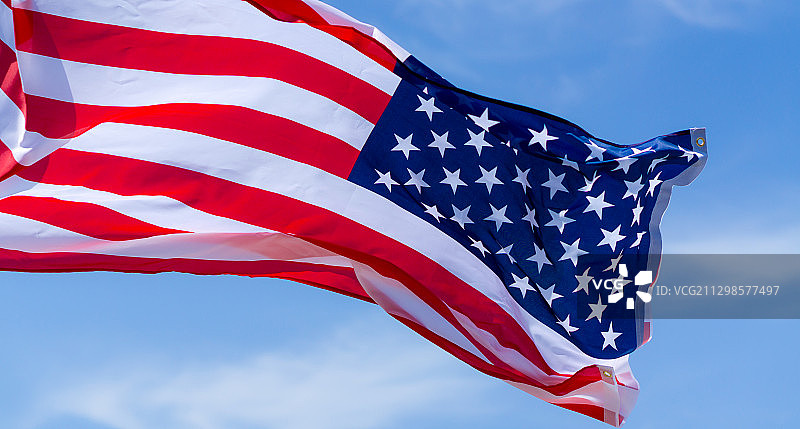 仰视角度拍摄的美国国旗，背景为蓝色天空图片素材