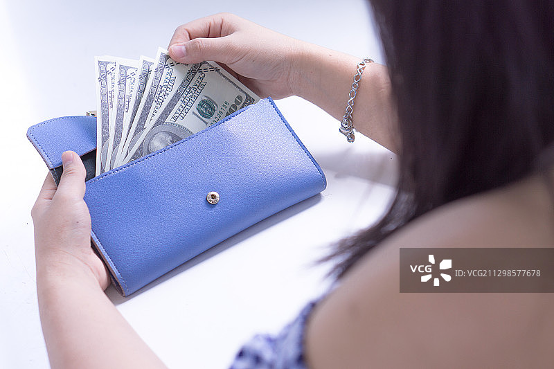 女人从蓝色钱包里拿出钱付款图片素材