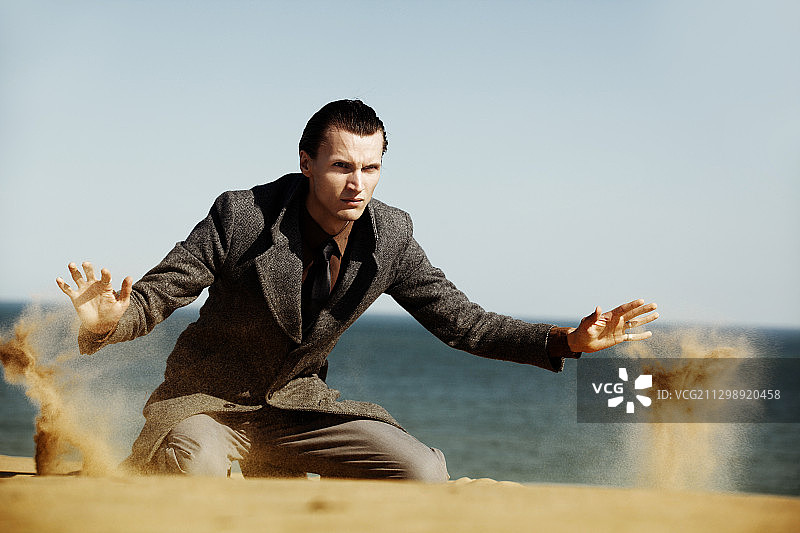 英俊且穿着考究的男人用手漏沙图片素材