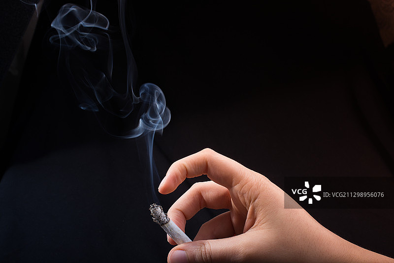 手持香烟，黑色背景图片素材