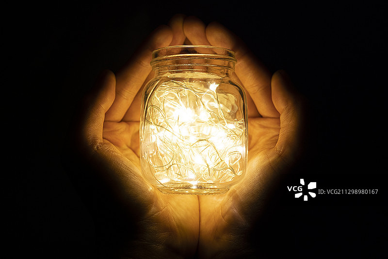 在暗室中手持发光串灯的特写图片素材