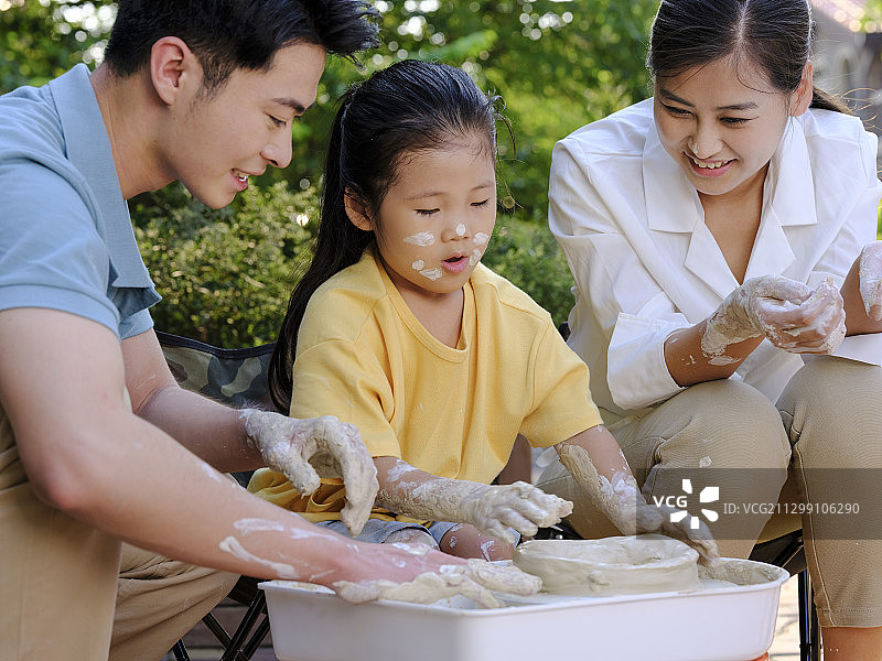 快乐的三口之家在户外一起做陶艺图片素材