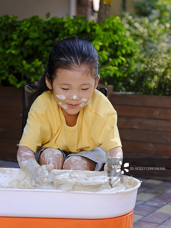 一个可爱的孩子在户外做陶艺图片素材