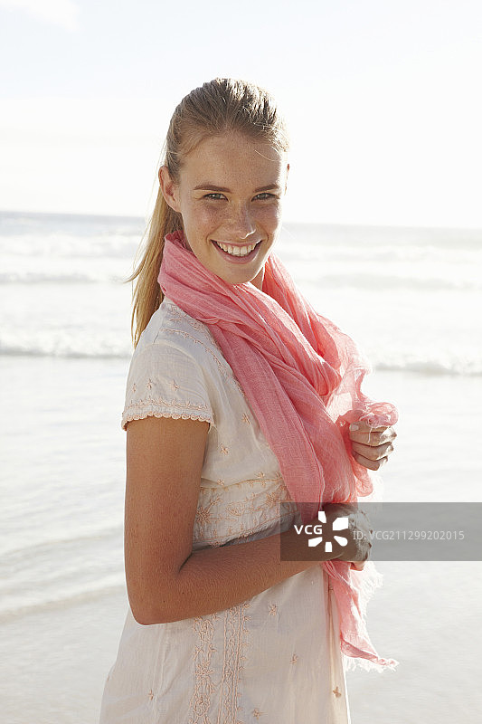 海边戴着粉红色围巾和白色连衣裙的金发女人图片素材