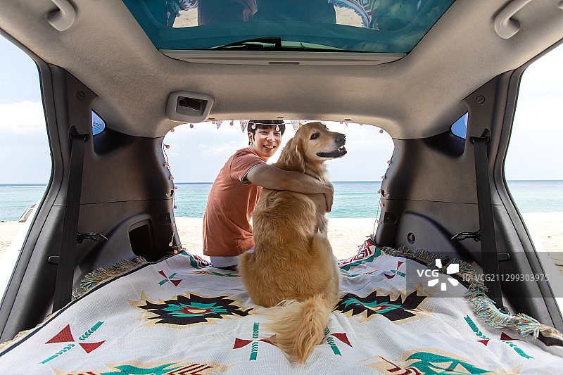 男人和金毛宠物狗在后备箱里露营图片素材