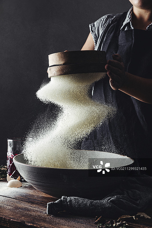 在木桌上筛意大利面粉的女人图片素材