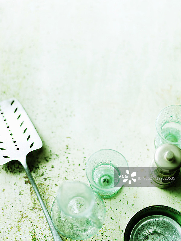 绿色表面上的餐具（铲子、玻璃杯、胡椒研磨器）图片素材