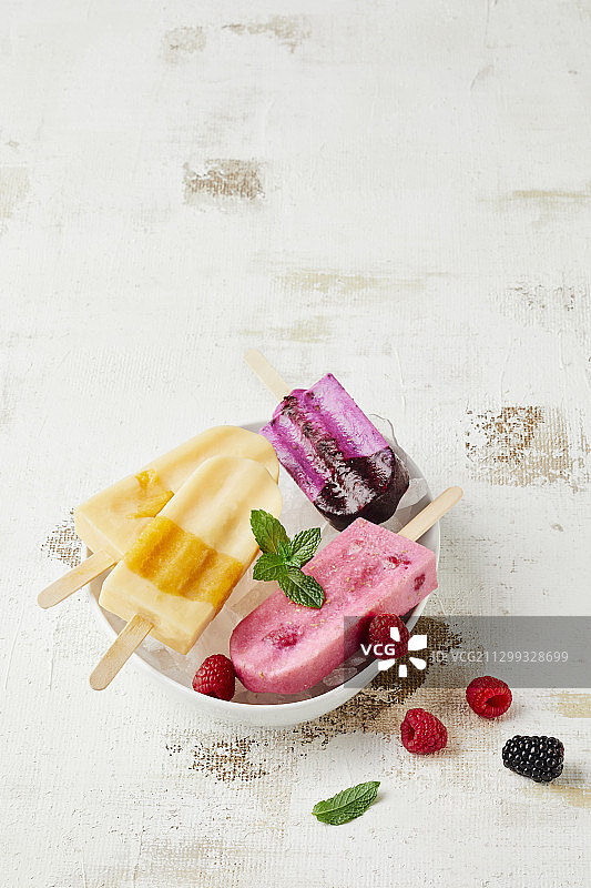 冰块碗里的各种冰棒（酪乳、覆盆子、黑莓、杏子）图片素材