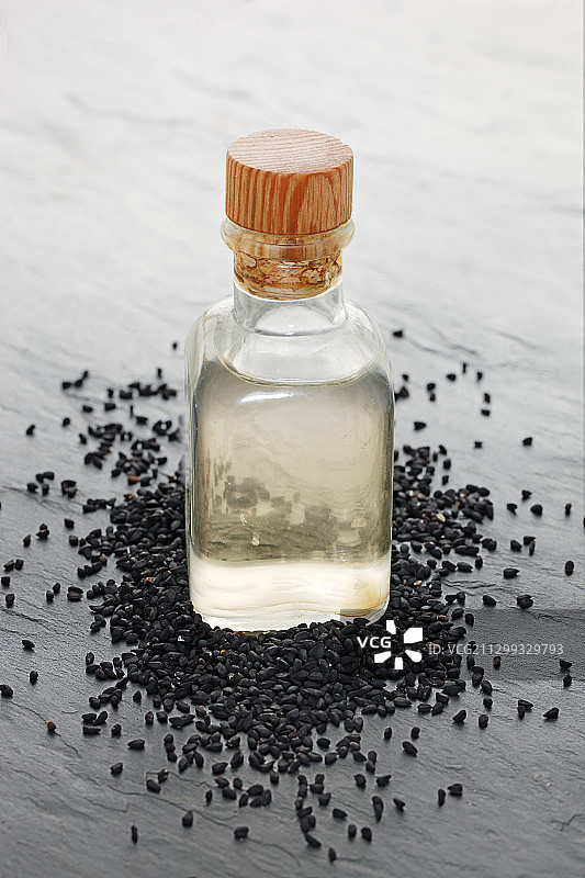 黑芝麻籽环绕的芝麻油瓶图片素材