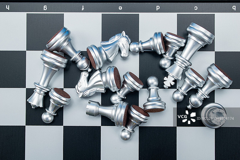 格子棋盘上的国际象棋倒下的银色棋子图片素材