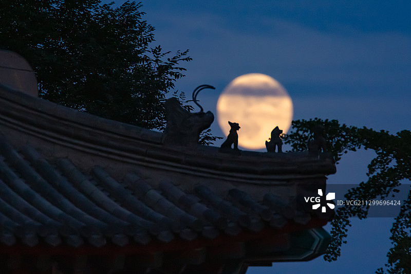 2020年6月5日，北京街头古建筑，满月从屋檐脊兽背后升起。图片素材