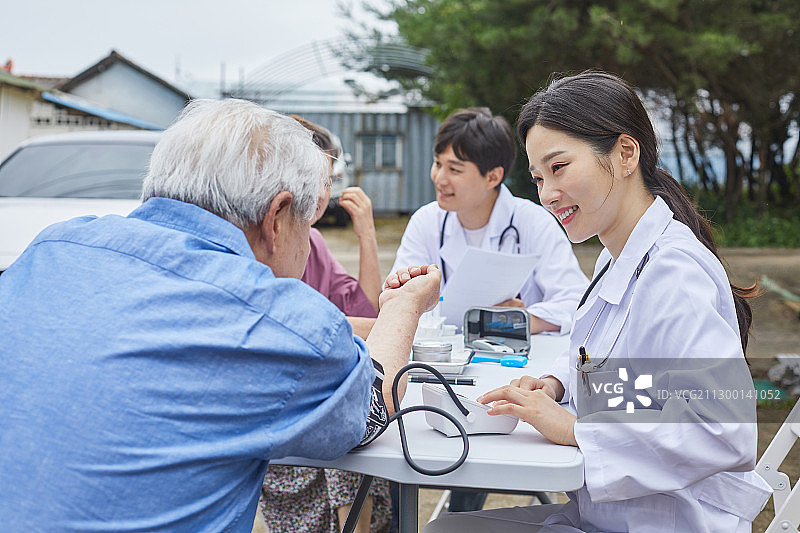 医疗服务：志愿者、医生进行检查，使用血压计进行测量和讲解图片素材