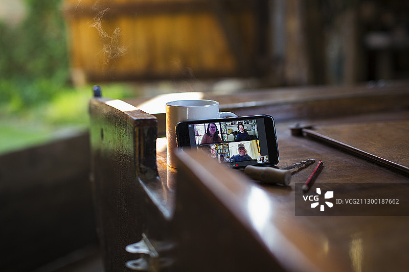 同事在木船上通过智能手机屏幕进行视频聊天图片素材