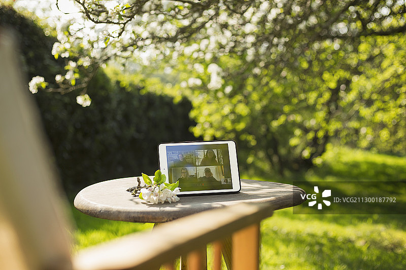 朋友们在阳光明媚的花园里通过平板电脑进行视频聊天图片素材