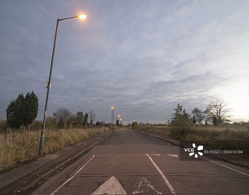 黄昏时分的空旷道路，位于郊区，有路灯图片素材