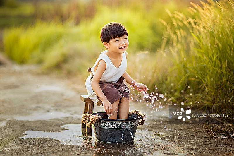 夏天穿白色背心洗脚玩水的小男孩图片素材