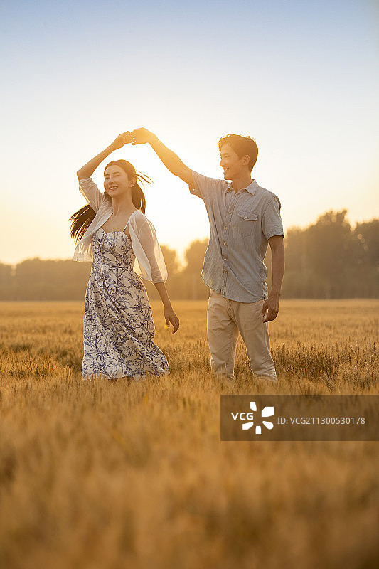 快乐的年轻情侣在麦田约会图片素材