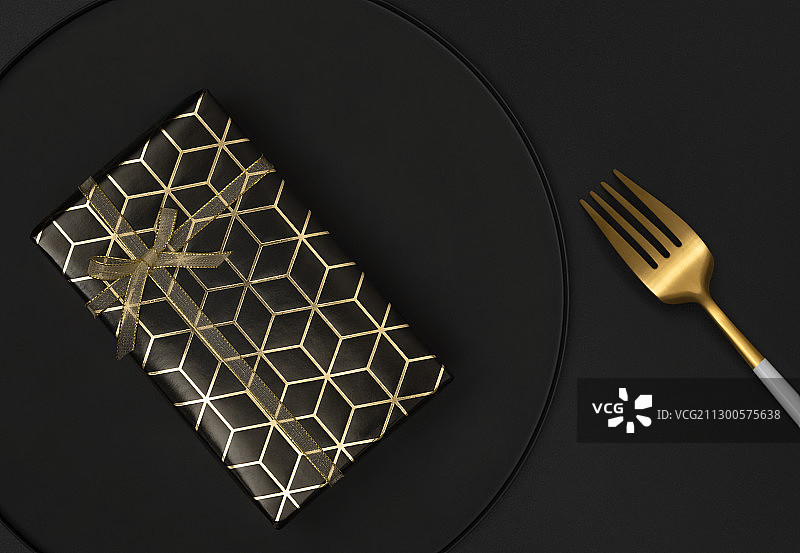 黑色背景盘子里的黑金礼物盒与叉子图片素材