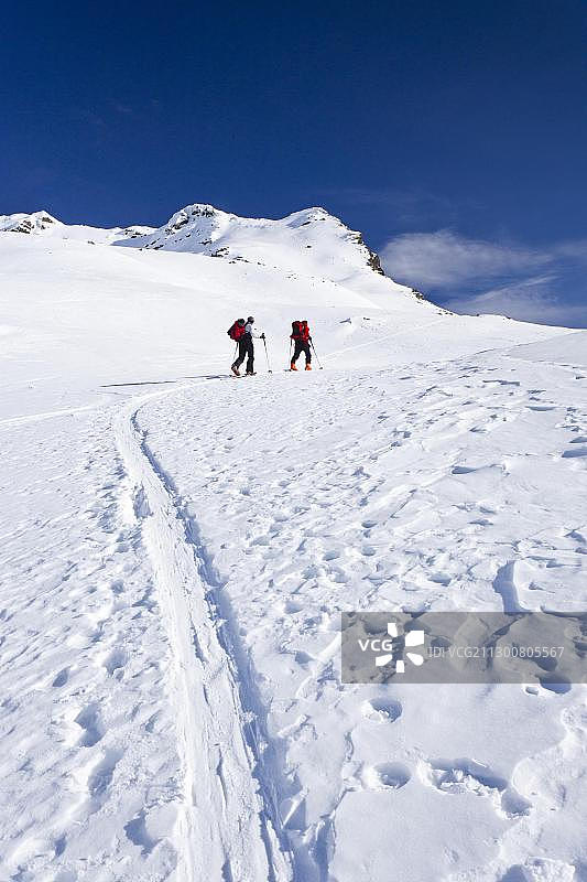 滑雪登山者在攀登霍特拉赫纳山，位于欧洲意大利南蒂罗尔萨恩塔尔山谷的杜恩霍尔茨上方图片素材