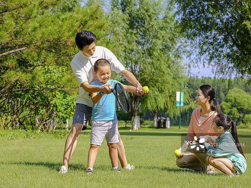 快乐的四口之家在公园打网球图片素材