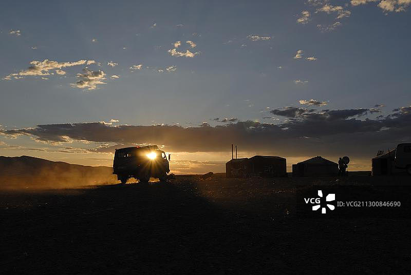 在戈壁沙漠的余晖中，俄罗斯四轮货车抵达蒙古国戈壁沙漠的蒙古包营地图片素材