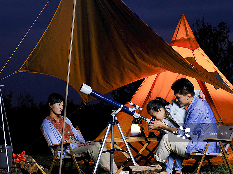 快乐的三口之家在户外使用天文望远镜图片素材