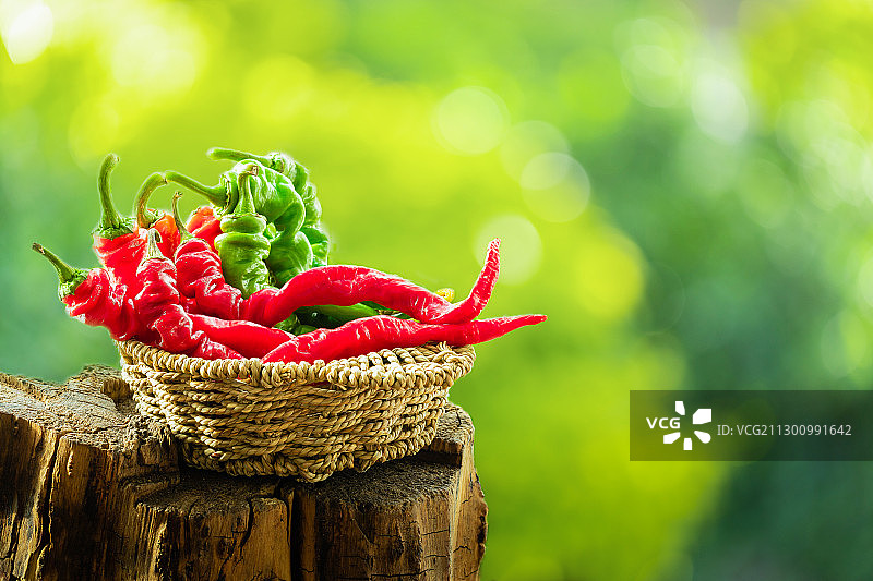 放在老树桩上的一篮子红色绿色螺丝椒特写图片素材