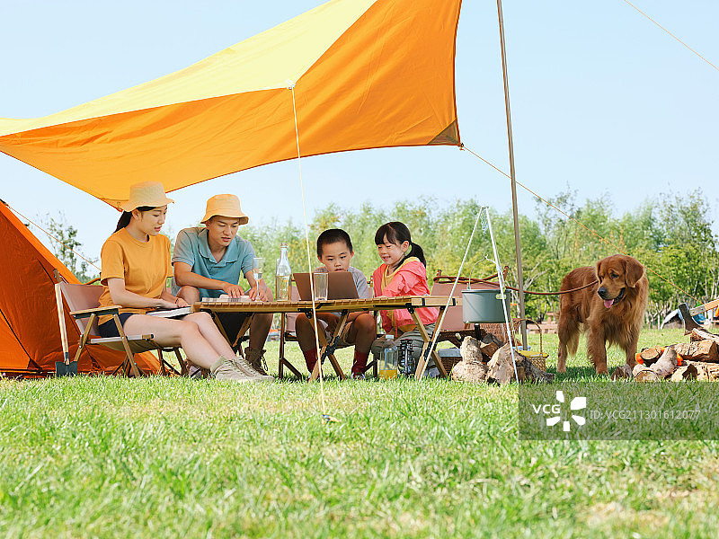 快乐的四口之家和宠物狗在户外露营图片素材