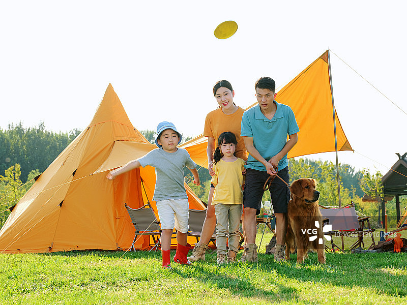 快乐的四口之家和宠物狗在公园玩耍图片素材