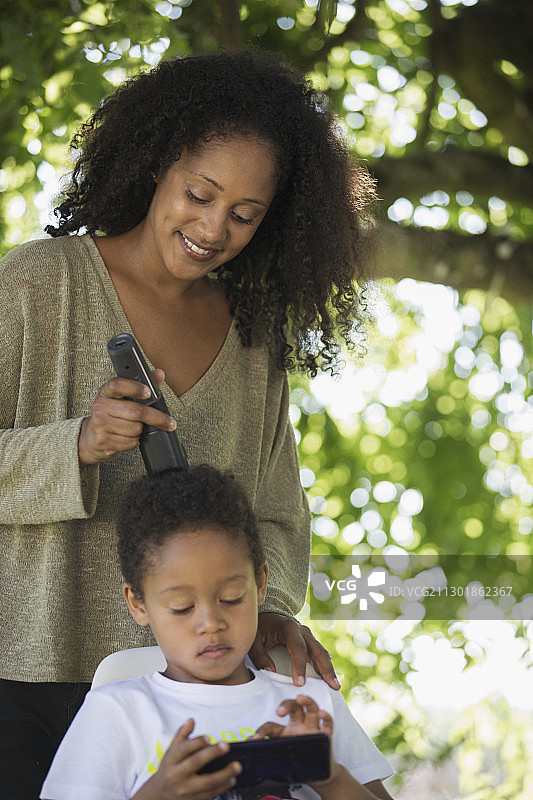 母亲在后院的树下给儿子理发图片素材