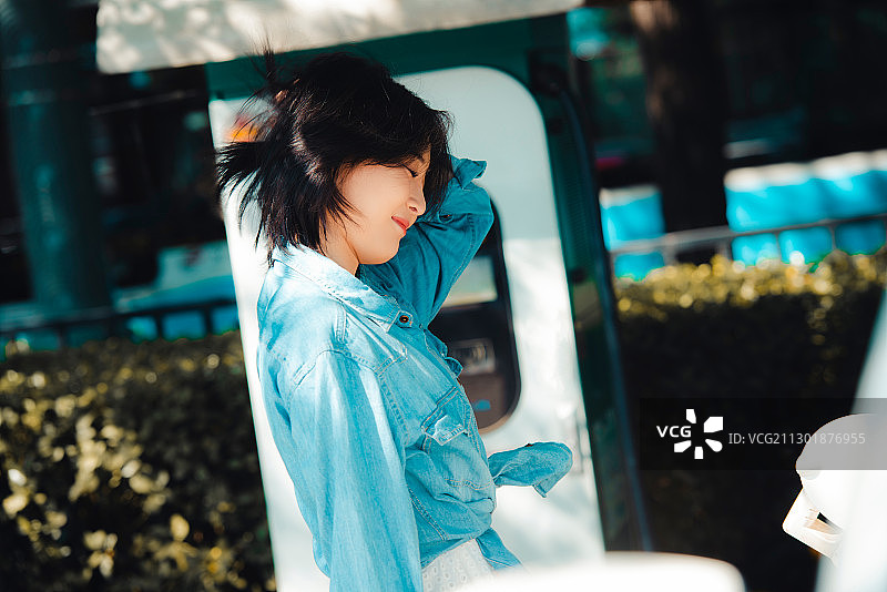 青年女性在给电动汽车充电图片素材