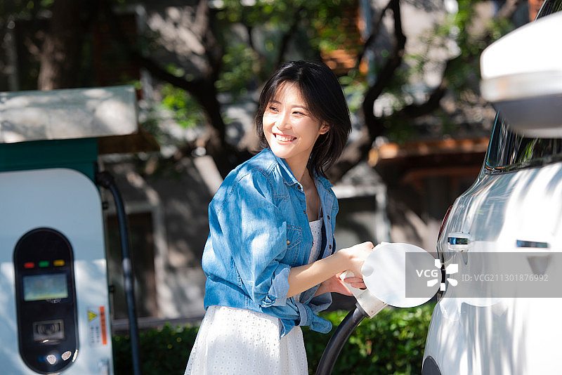 青年女性在给电动车充电图片素材