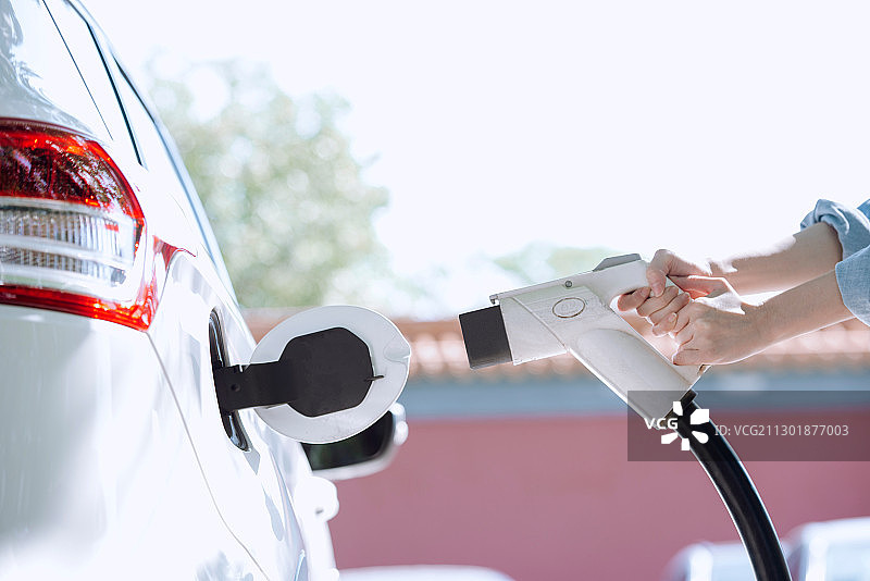 青年女性给电动车充电的特写图片素材
