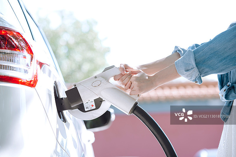 青年女性给电动车充电的特写图片素材