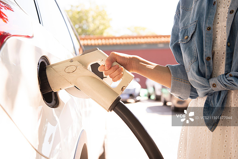 青年女性给电动车充电的特写图片素材