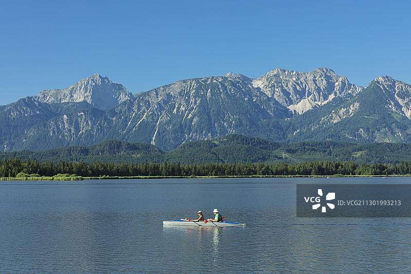 在德国上巴伐利亚阿尔高阿尔卑斯山福森附近的霍普芬湖上划皮划艇图片素材