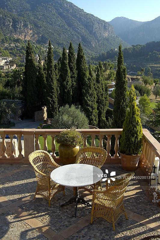 西班牙马略卡岛瓦尔德莫萨的庭院，配有桌椅和柏树图片素材