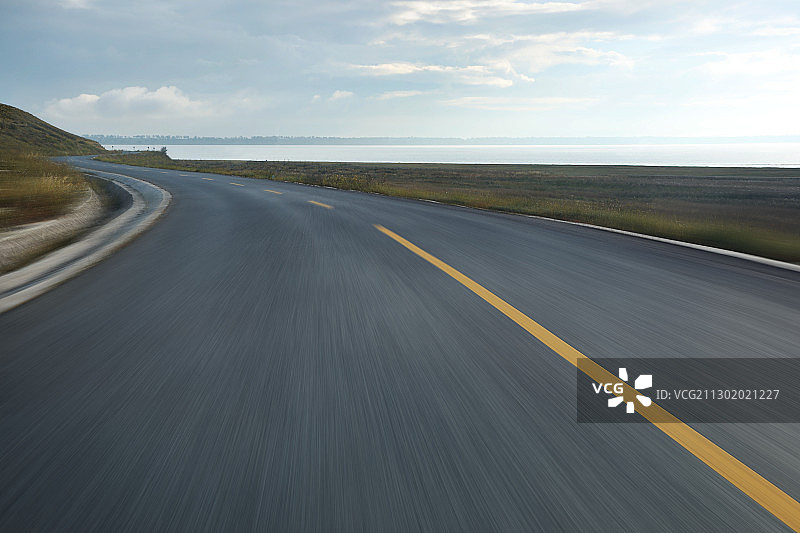 日出时分飞驰的湖边公路图片素材