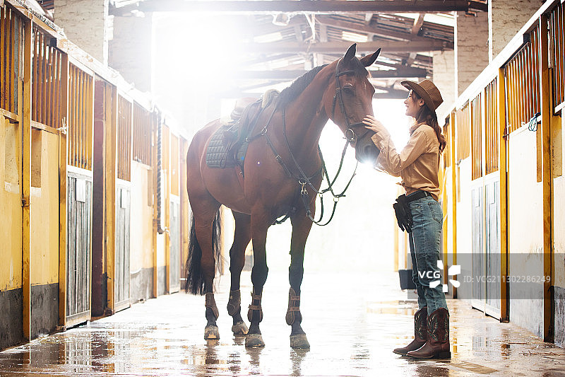 马厩走廊里快乐的青年女人和马图片素材