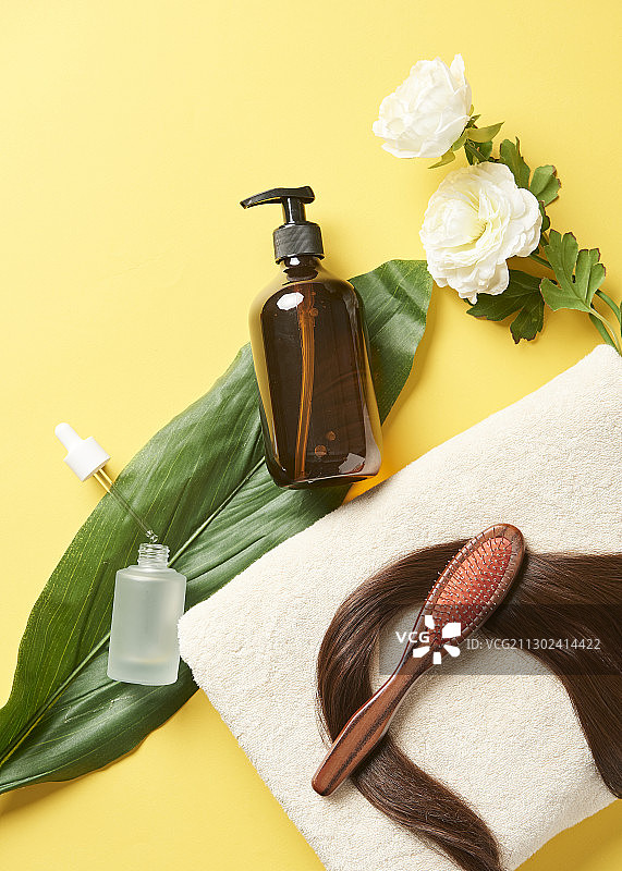 毛巾和树叶上精油和发刷等头发护理产品，鲜花点缀图片素材
