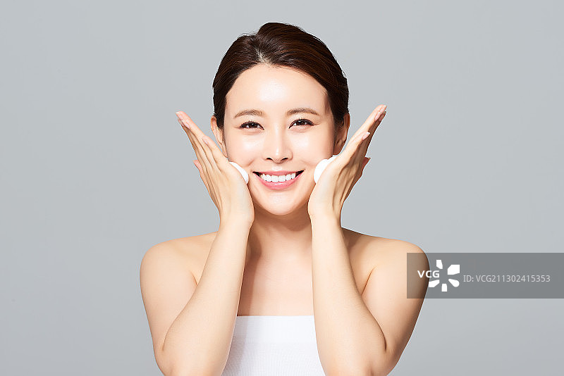 笑容灿烂，涂抹泡沫的年轻女子，穿着白色抹胸图片素材