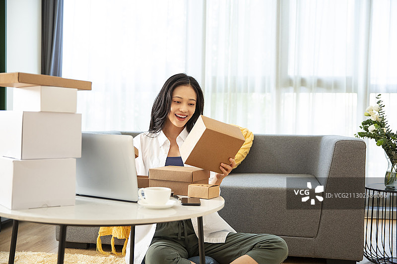 年轻女子在客厅拿着快递盒子图片素材