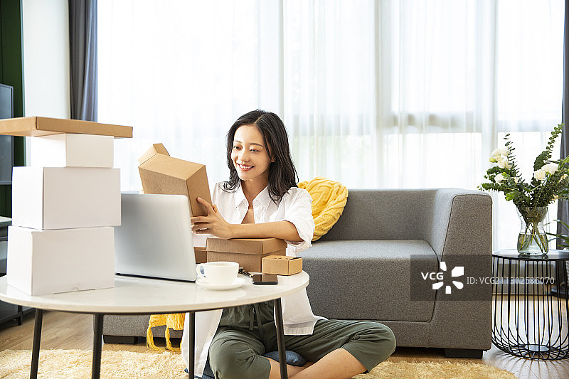 年轻女子在客厅拿着快递盒子图片素材