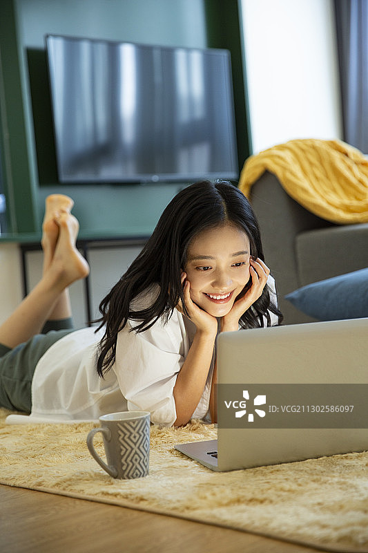 青年女子在客厅使用笔记本电脑工作图片素材