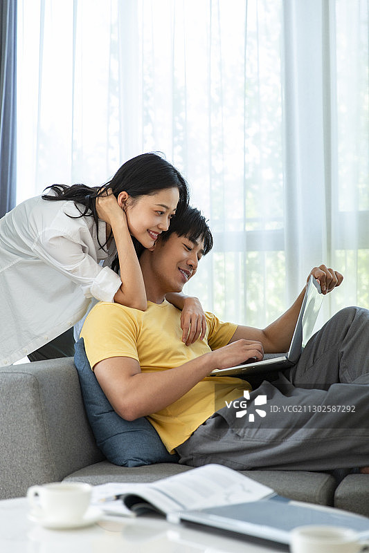 年轻情侣使用笔记本电脑居家远程办公图片素材